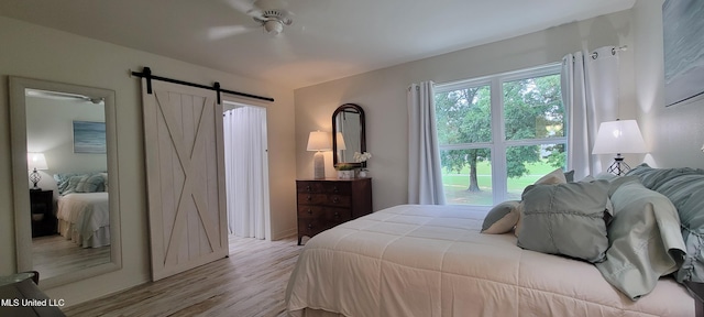 417 Highpoint Dr, Diamondhead, MS 39525 - bedroom with a barn door, wood finished floors, and a ceiling fan