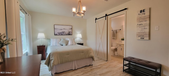 417 Highpoint Dr, Diamondhead, MS 39525 - bedroom with a barn door, light wood-style floors, a chandelier, and connected bathroom