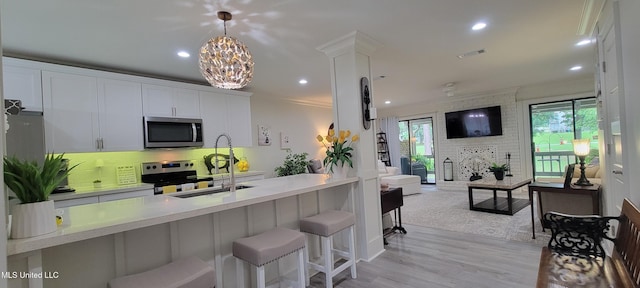 417 Highpoint Dr, Diamondhead, MS 39525 - kitchen with stainless steel appliances, open floor plan, light countertops, white cabinetry, and a breakfast bar area