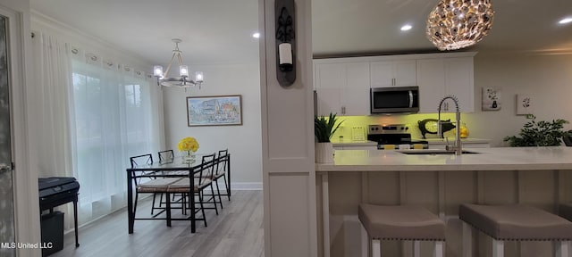 417 Highpoint Dr, Diamondhead, MS 39525 - kitchen with a chandelier, stainless steel appliances, ornamental molding, a sink, and light wood-type flooring