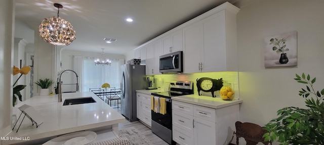 417 Highpoint Dr, Diamondhead, MS 39525 - kitchen featuring stainless steel appliances, a chandelier, a sink, white cabinets, and recessed lighting