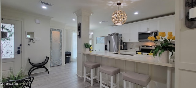417 Highpoint Dr, Diamondhead, MS 39525 - kitchen featuring appliances with stainless steel finishes, backsplash, a peninsula, a kitchen bar, and white cabinetry
