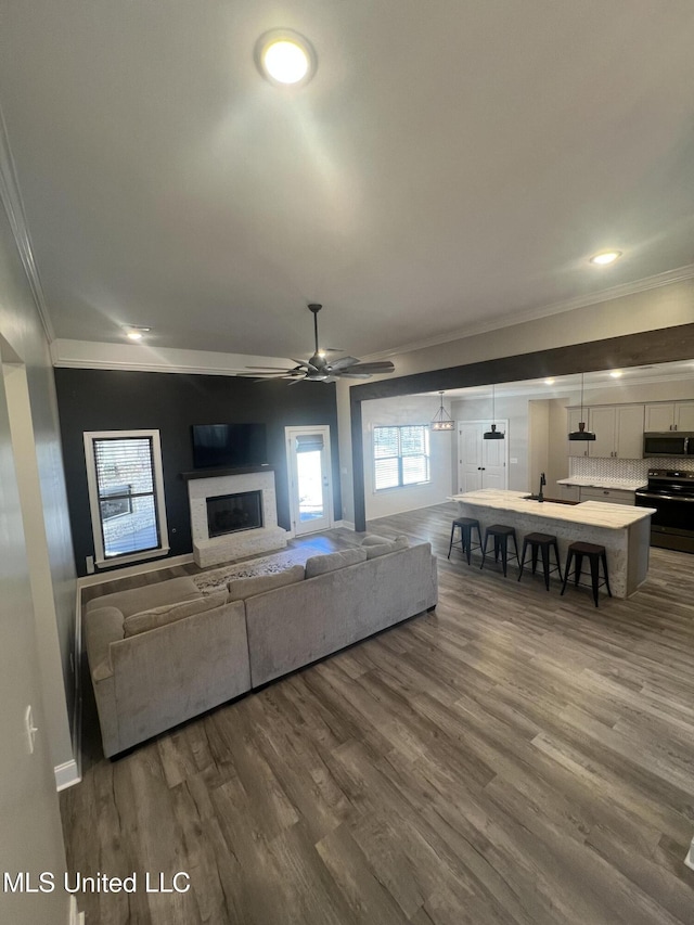 11368 Cedar Point Cv, Hernando, MS 38632 - living room featuring crown molding, dark wood-type flooring, a fireplace with raised hearth, ceiling fan, and baseboards