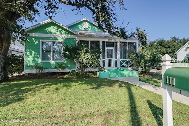 rear view of house with a yard and a sunroom