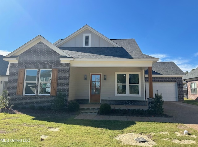 view of front of house with a front yard, a garage, and a porch