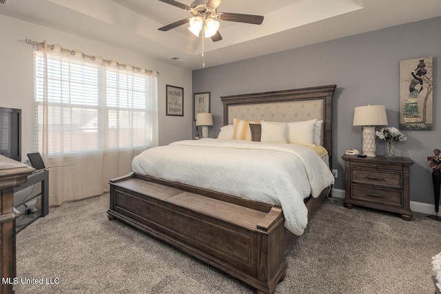 carpeted bedroom with a raised ceiling and ceiling fan