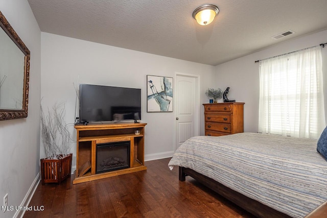 bedroom with dark hardwood / wood-style floors and a textured ceiling