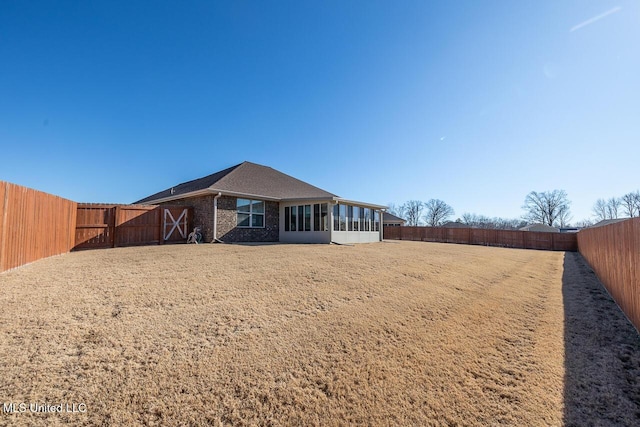 rear view of house featuring a sunroom and a lawn