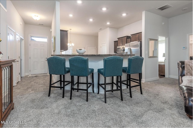 kitchen with hanging light fixtures, appliances with stainless steel finishes, a kitchen breakfast bar, and kitchen peninsula