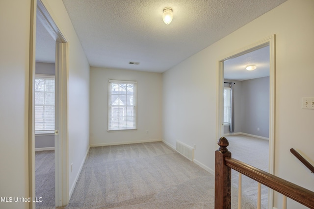 carpeted spare room with a textured ceiling