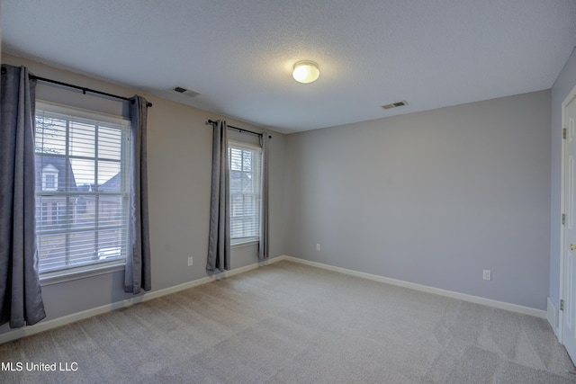 carpeted empty room featuring a textured ceiling