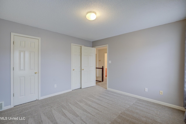 unfurnished bedroom with light carpet, a closet, and a textured ceiling