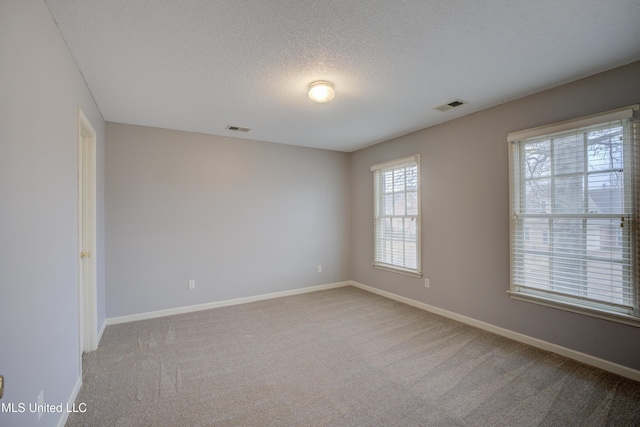 carpeted empty room featuring a textured ceiling