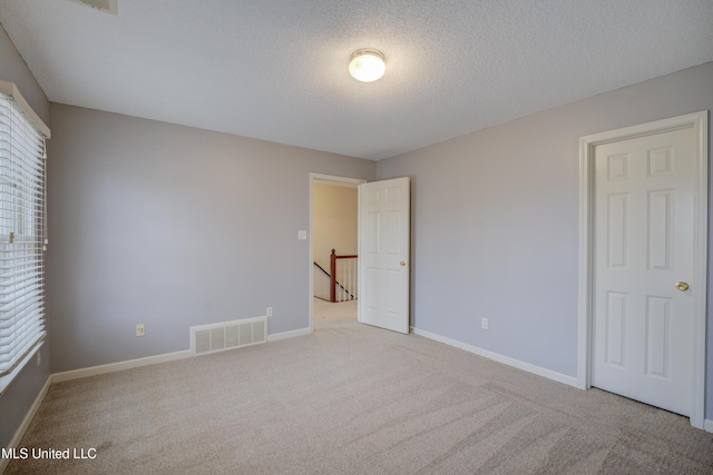 unfurnished bedroom with light colored carpet and a textured ceiling