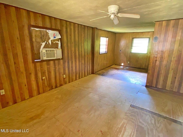 empty room featuring ceiling fan, wood walls, and cooling unit