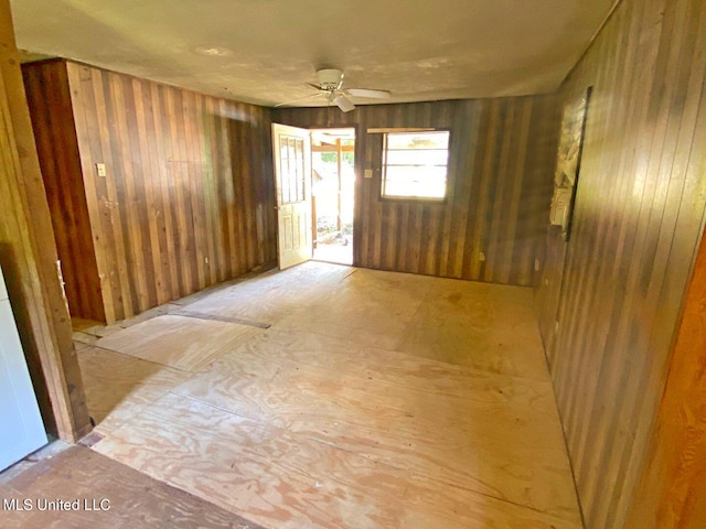 unfurnished room with ceiling fan and wooden walls