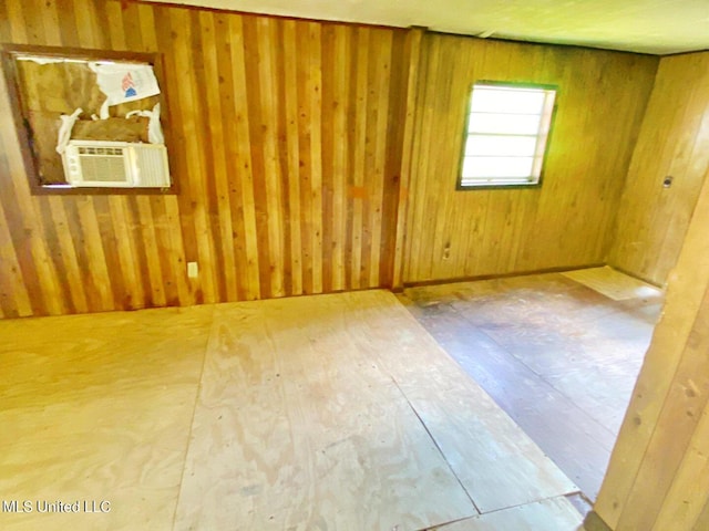 unfurnished room with cooling unit and wood walls