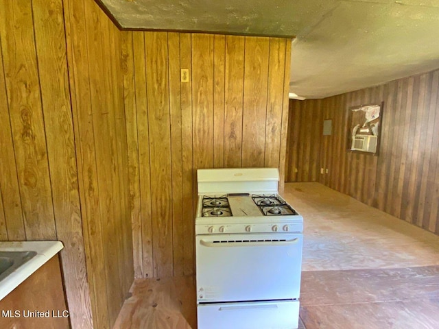 kitchen featuring brown cabinetry, wooden walls, and gas range gas stove