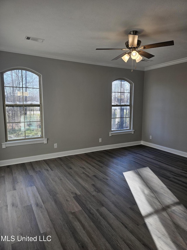 spare room featuring dark wood finished floors, crown molding, and baseboards