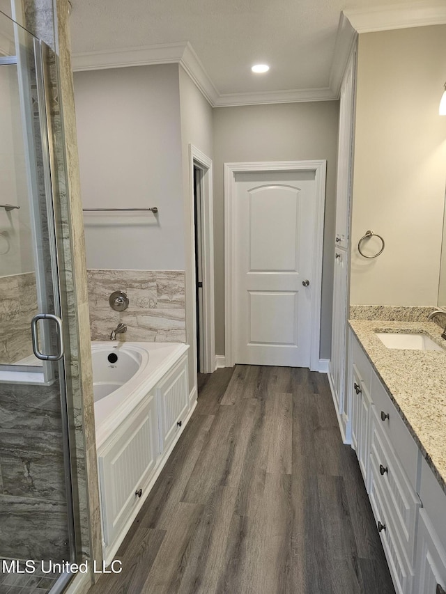 full bath featuring a stall shower, wood finished floors, a garden tub, and ornamental molding