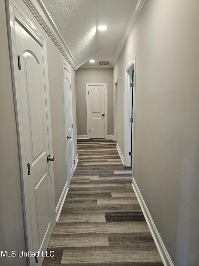 hall with visible vents, ornamental molding, a textured ceiling, dark wood finished floors, and baseboards