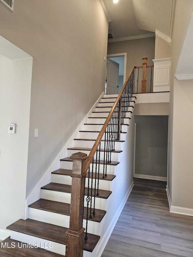 stairway with visible vents, baseboards, wood finished floors, and crown molding