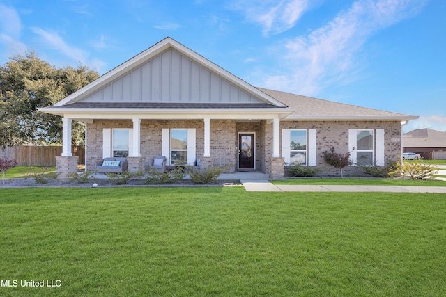 view of front of home featuring covered porch, a front lawn, board and batten siding, and brick siding