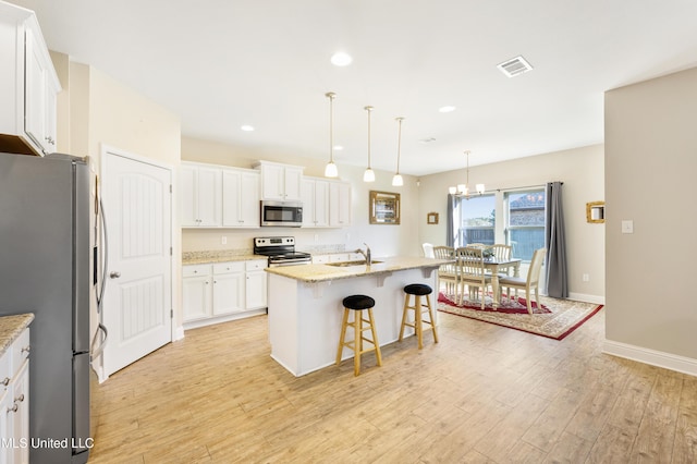 kitchen with light stone counters, appliances with stainless steel finishes, a center island with sink, and white cabinetry