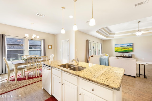 kitchen featuring visible vents, a center island with sink, hanging light fixtures, and stainless steel dishwasher