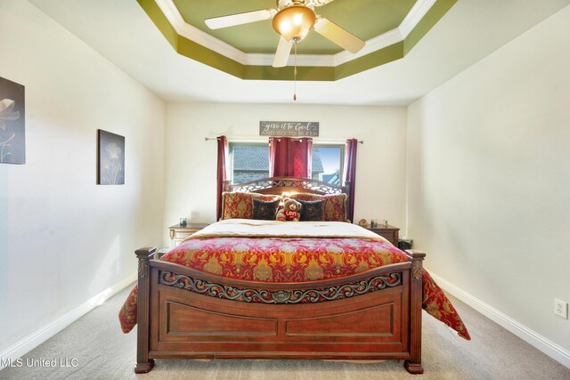 bedroom featuring baseboards, light carpet, a raised ceiling, and crown molding