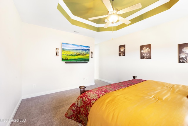 carpeted bedroom with baseboards, visible vents, a raised ceiling, and a ceiling fan