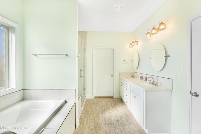 full bath featuring a garden tub, a shower stall, a sink, and wood finished floors