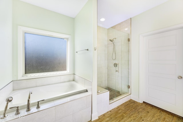 bathroom with a stall shower, a garden tub, and wood finished floors