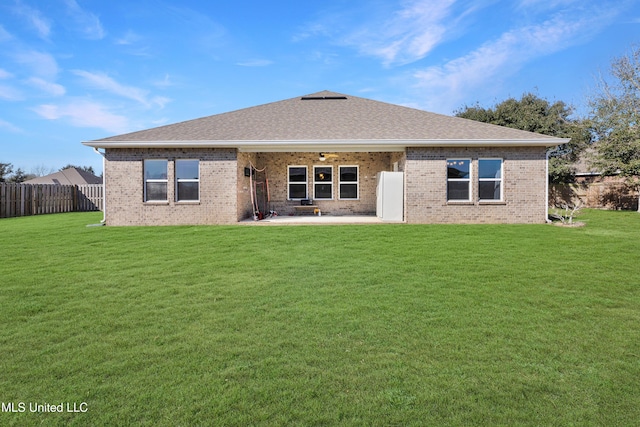 back of property with fence private yard, brick siding, a yard, and a patio