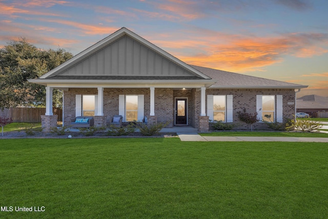 view of front facade featuring a porch, a front lawn, and brick siding