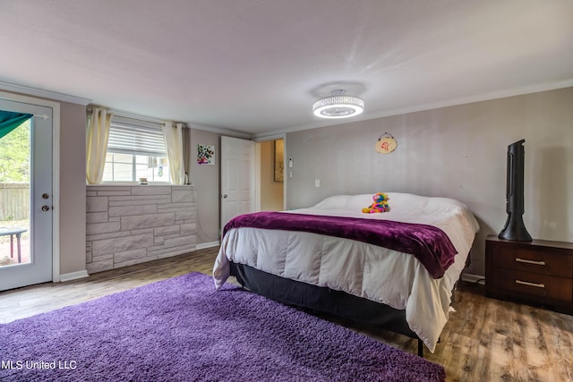 bedroom with crown molding, hardwood / wood-style floors, and access to exterior