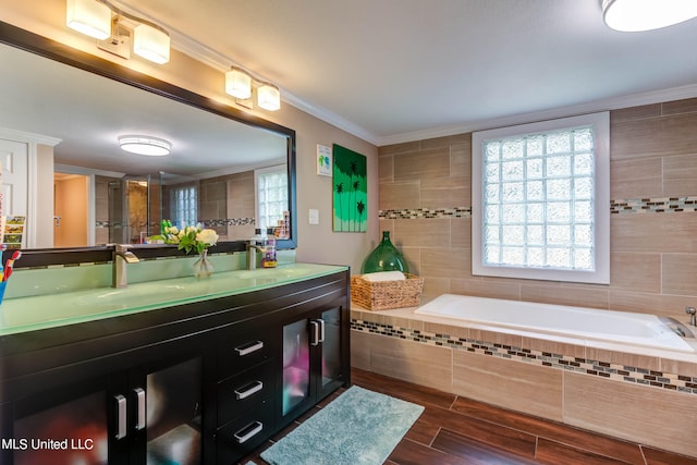 bathroom featuring vanity, ornamental molding, hardwood / wood-style flooring, and tiled tub