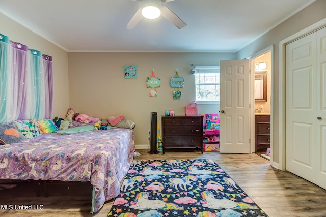 bedroom featuring ceiling fan, connected bathroom, light wood-type flooring, ornamental molding, and a closet