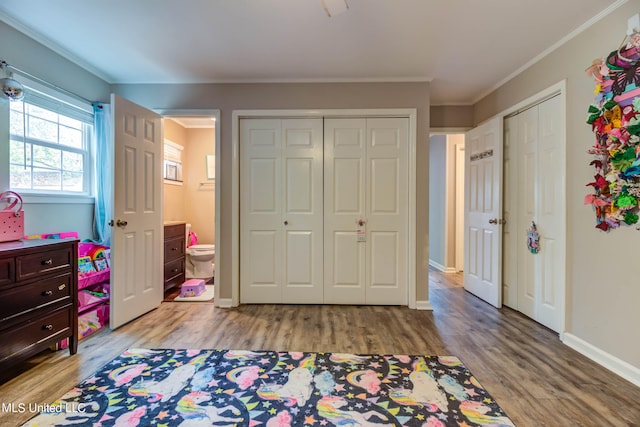 bedroom featuring connected bathroom, ornamental molding, and light wood-type flooring