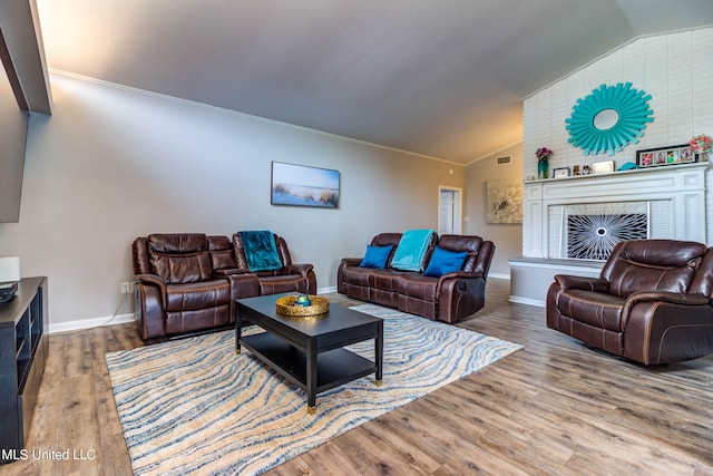 living room with lofted ceiling, wood-type flooring, a fireplace, and crown molding