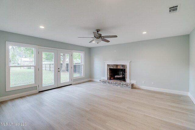 unfurnished living room with ceiling fan, french doors, light hardwood / wood-style floors, and a brick fireplace