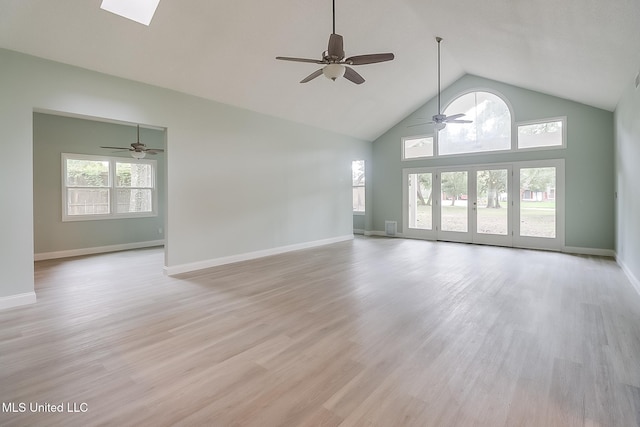 unfurnished living room featuring ceiling fan, a healthy amount of sunlight, high vaulted ceiling, and light hardwood / wood-style flooring