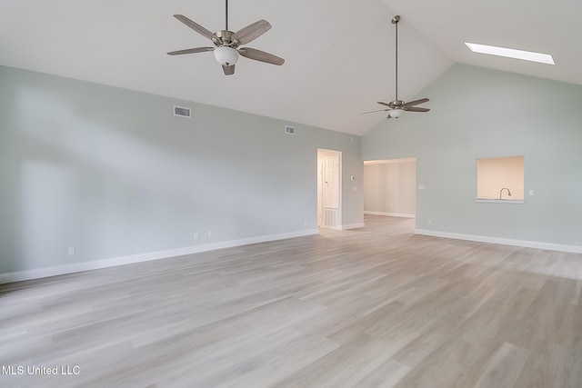 spare room with ceiling fan, light wood-type flooring, high vaulted ceiling, and a skylight