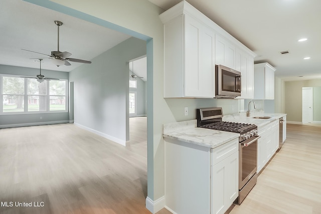 kitchen with sink, white cabinets, light hardwood / wood-style flooring, and appliances with stainless steel finishes