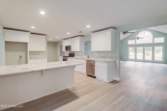 kitchen with white cabinetry, light hardwood / wood-style flooring, stainless steel appliances, and vaulted ceiling