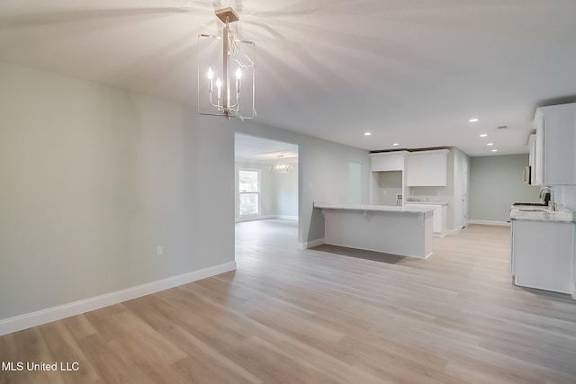 kitchen with an inviting chandelier, light hardwood / wood-style flooring, white cabinetry, and sink