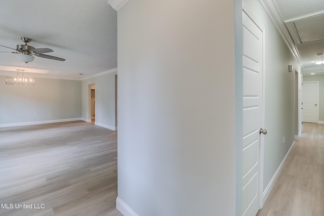 hallway with ornamental molding, a notable chandelier, and light wood-type flooring