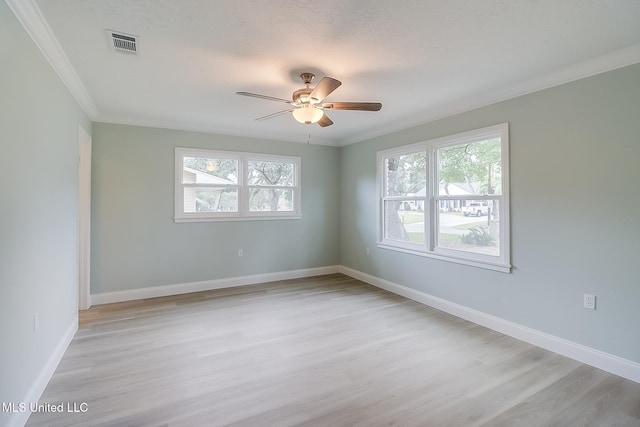 empty room with ceiling fan, ornamental molding, a healthy amount of sunlight, and light hardwood / wood-style floors