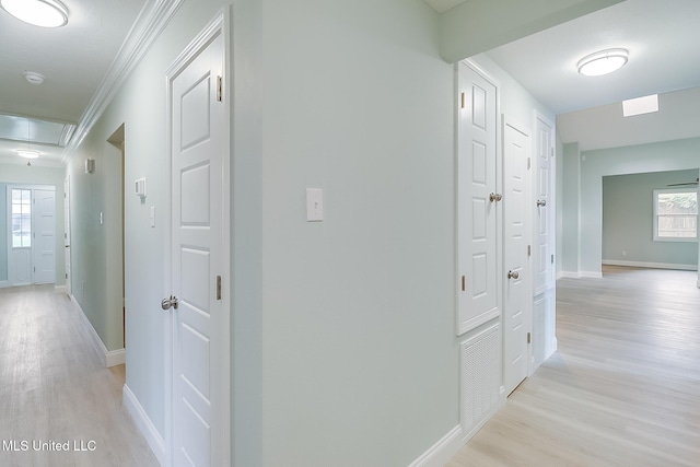 hall with light wood-type flooring and ornamental molding