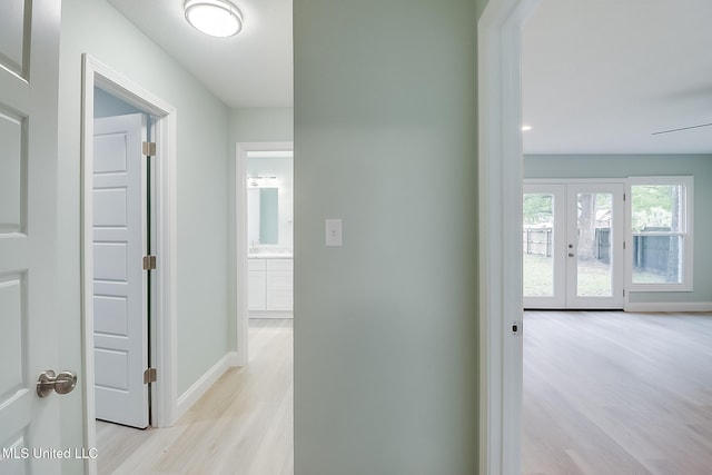 corridor with french doors and light hardwood / wood-style flooring